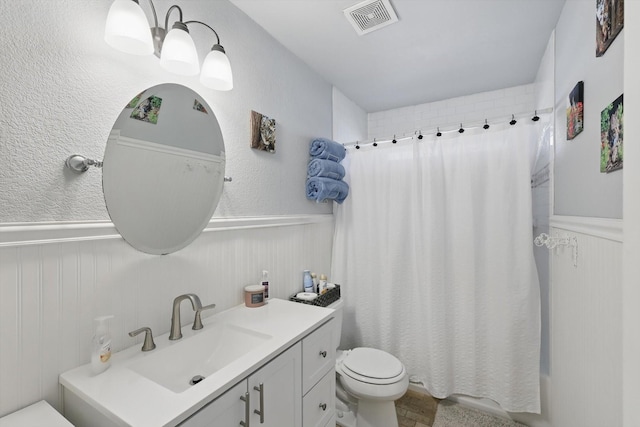 bathroom with vanity, toilet, visible vents, and wainscoting