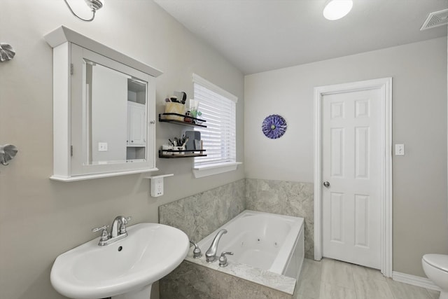 bathroom featuring a sink, visible vents, toilet, and a jetted tub