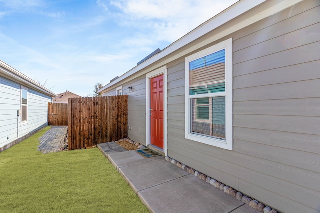 entrance to property featuring a yard and fence