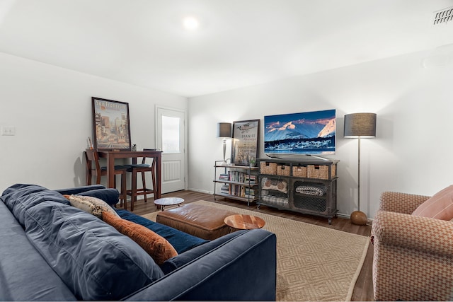 living room with wood finished floors, visible vents, and baseboards