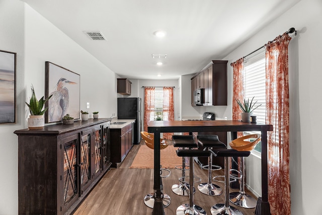 kitchen featuring visible vents, dark brown cabinetry, stainless steel appliances, and light wood finished floors