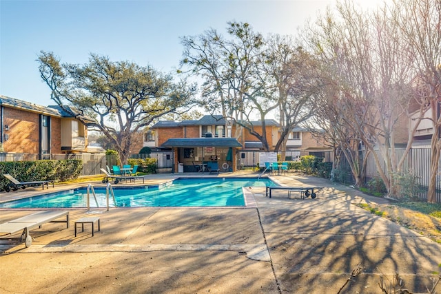 community pool featuring a residential view, fence, and a patio area