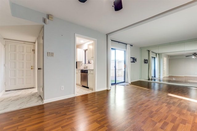 unfurnished living room featuring light wood-style flooring, baseboards, and ceiling fan