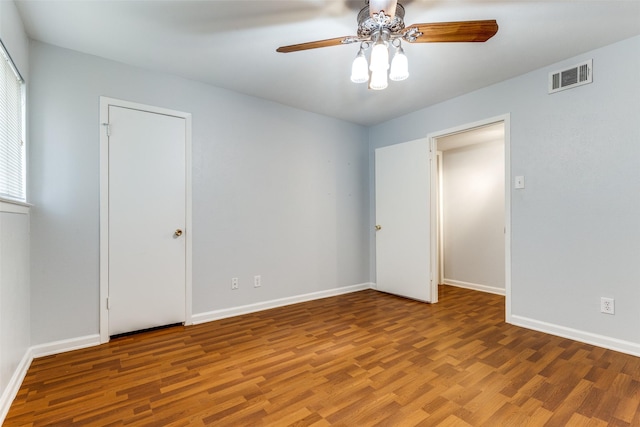 spare room with ceiling fan, visible vents, baseboards, and wood finished floors