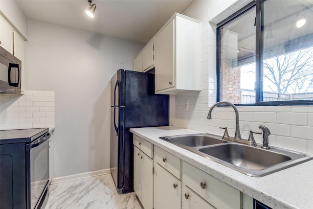 kitchen featuring marble finish floor, black appliances, a sink, light countertops, and baseboards