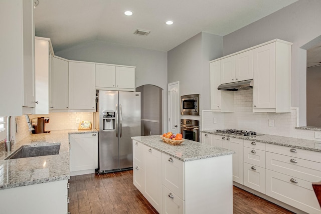 kitchen with visible vents, under cabinet range hood, a sink, arched walkways, and appliances with stainless steel finishes