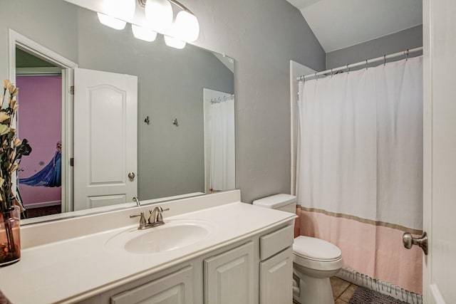 bathroom with tile patterned flooring, toilet, vanity, and lofted ceiling