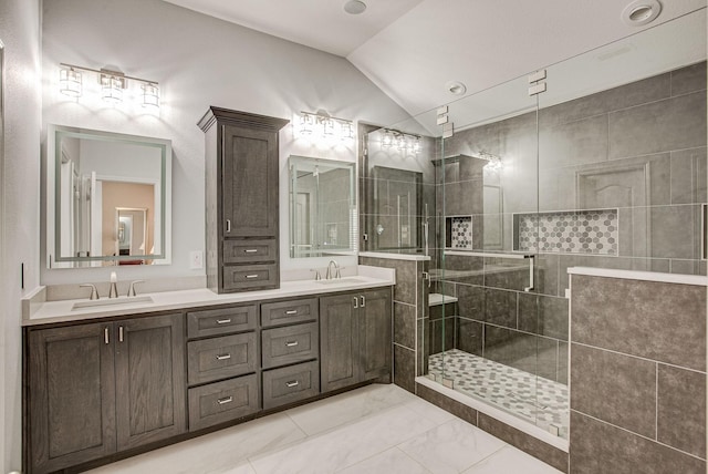 bathroom with double vanity, a sink, a stall shower, and vaulted ceiling