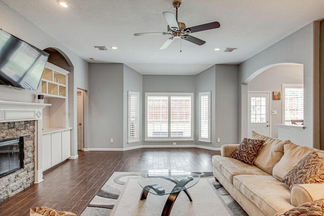 living area featuring dark wood-style floors, visible vents, a fireplace, and baseboards