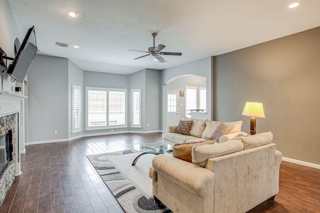 living room featuring dark wood finished floors, visible vents, a fireplace, and baseboards