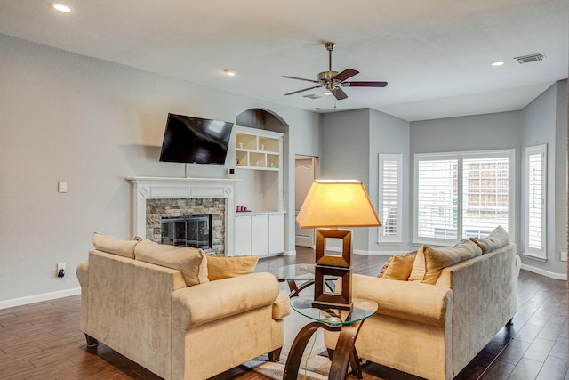 living room featuring a fireplace, visible vents, dark wood-style flooring, and baseboards