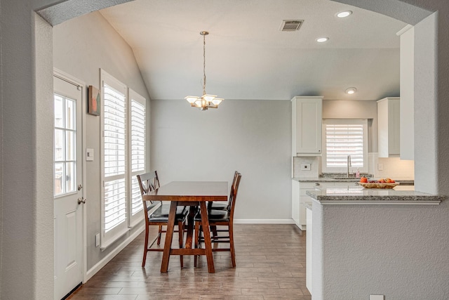 dining area featuring visible vents, lofted ceiling, dark wood-style floors, an inviting chandelier, and baseboards