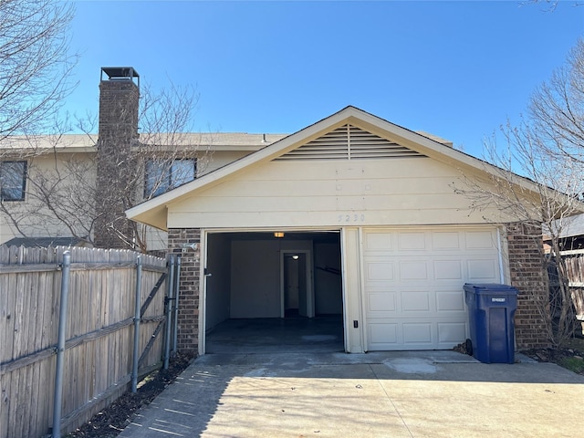 garage featuring concrete driveway and fence