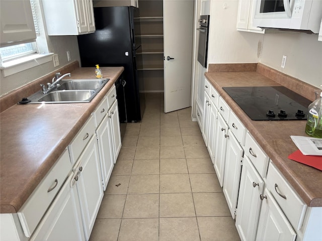 kitchen featuring light tile patterned floors, black appliances, white cabinets, and a sink