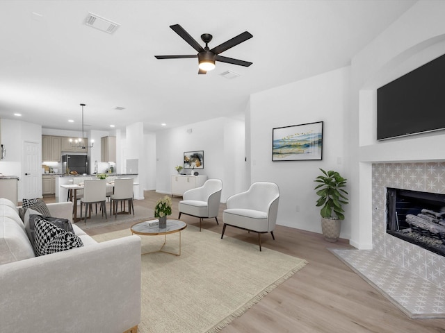 living area with light wood-type flooring, visible vents, recessed lighting, and a tile fireplace