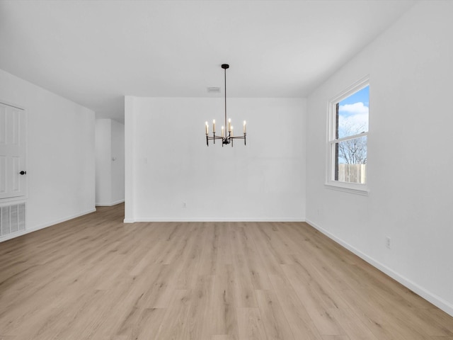 unfurnished dining area with a notable chandelier, visible vents, light wood-style flooring, and baseboards