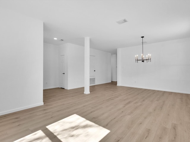 unfurnished living room with visible vents, an inviting chandelier, baseboards, and light wood-style floors