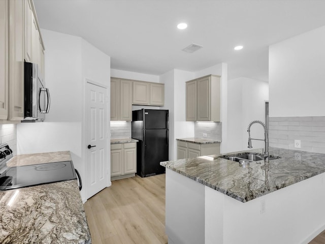 kitchen with light stone countertops, visible vents, a peninsula, a sink, and black appliances