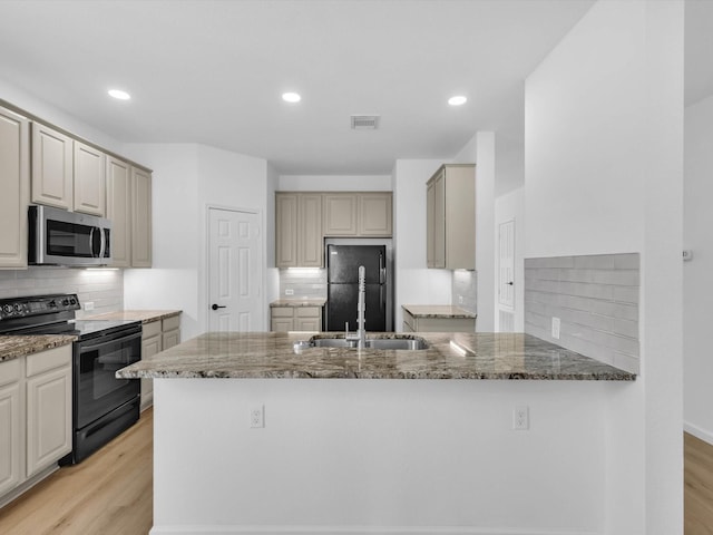 kitchen with visible vents, stone counters, a peninsula, and black appliances