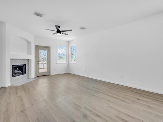 unfurnished living room with visible vents, light wood-style flooring, and a tile fireplace