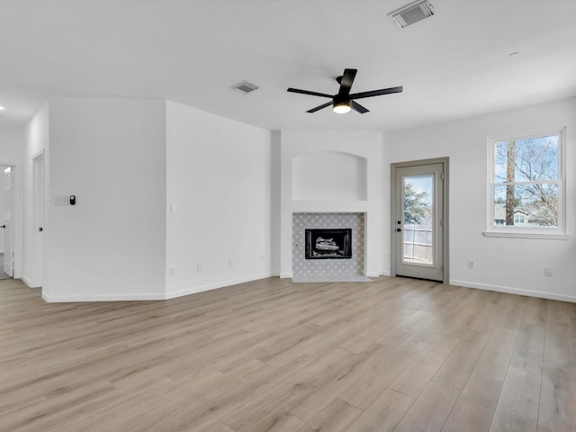 unfurnished living room with visible vents, a tile fireplace, a ceiling fan, and light wood-style floors