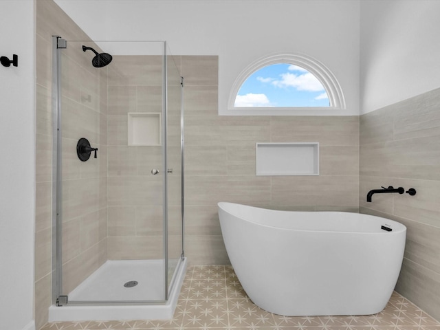 bathroom with a soaking tub, tile walls, and a stall shower