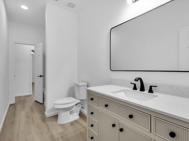 bathroom with visible vents, toilet, wood finished floors, baseboards, and vanity