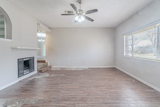 unfurnished living room with visible vents, a ceiling fan, a textured ceiling, wood finished floors, and a fireplace