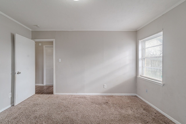 carpeted spare room featuring baseboards and ornamental molding