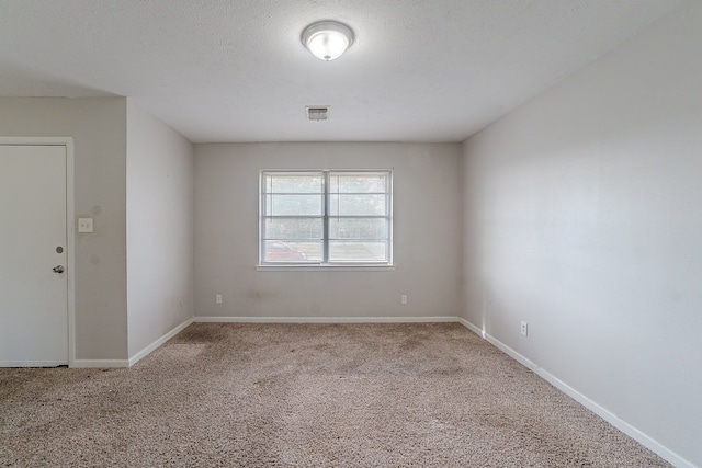 carpeted spare room featuring visible vents, baseboards, and a textured ceiling