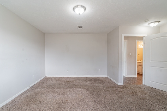 unfurnished room featuring baseboards, visible vents, a textured ceiling, and carpet