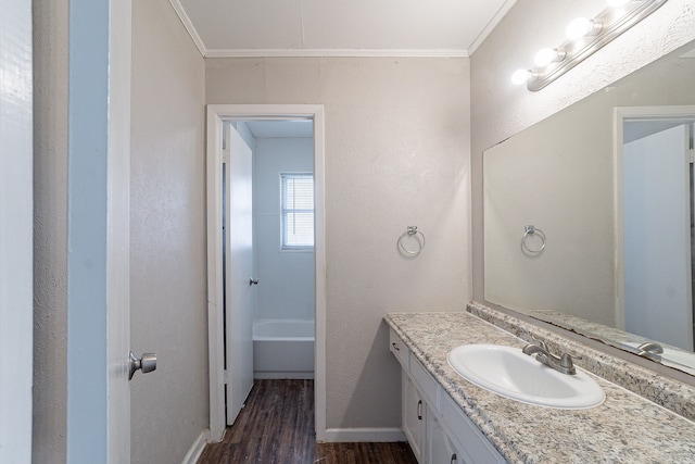 bathroom featuring a bathtub, vanity, wood finished floors, and crown molding