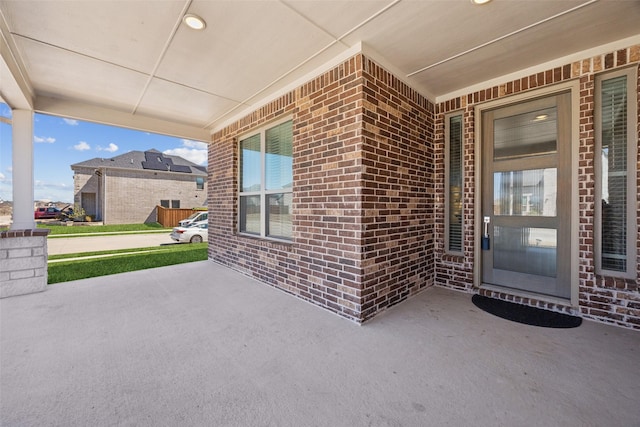 entrance to property featuring brick siding and covered porch