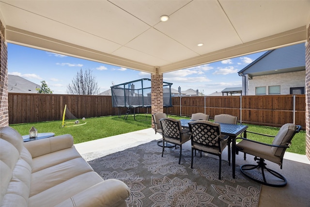 view of patio featuring outdoor lounge area, outdoor dining area, a fenced backyard, and a trampoline