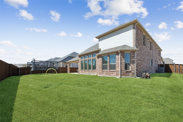 back of house featuring central air condition unit, brick siding, a fenced backyard, and a yard