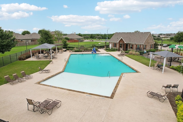 community pool with a patio area, a yard, and fence