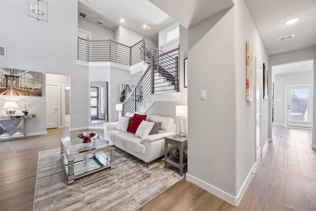 living room with visible vents, stairway, baseboards, and wood finished floors