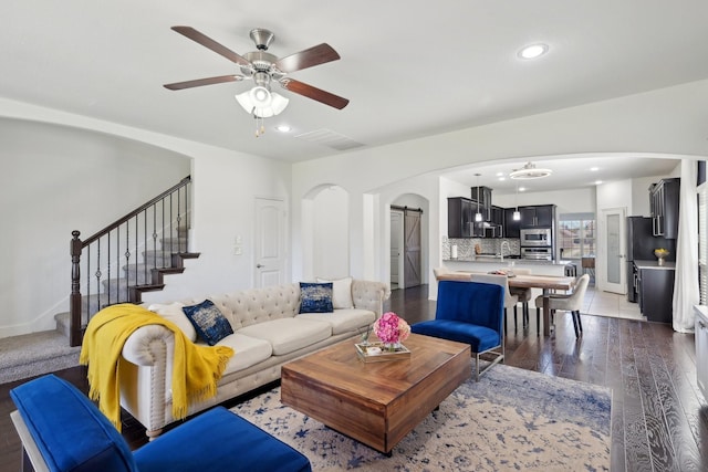 living room with visible vents, recessed lighting, arched walkways, stairs, and a barn door