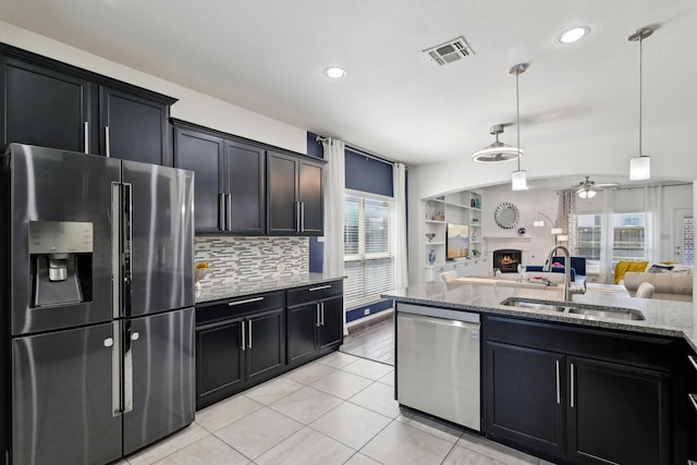 kitchen with visible vents, a sink, a lit fireplace, stainless steel appliances, and open floor plan