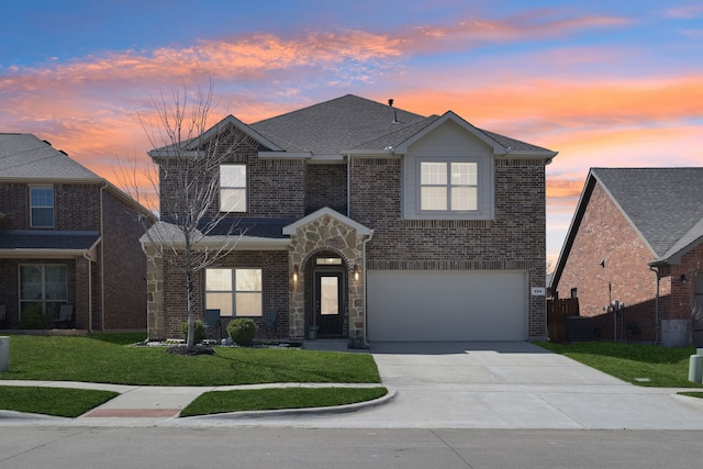 traditional-style home with brick siding, a shingled roof, a lawn, a garage, and driveway