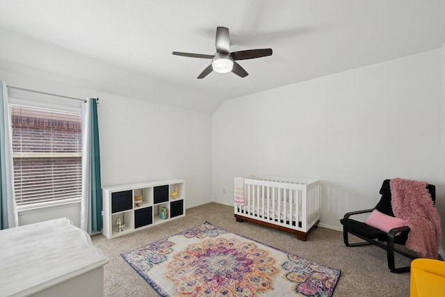 carpeted bedroom with baseboards, a crib, a ceiling fan, and vaulted ceiling