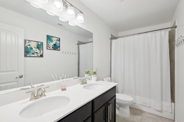 bathroom with double vanity, toilet, visible vents, and a sink