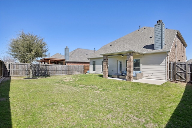 rear view of property with a shingled roof, a chimney, a fenced backyard, a yard, and a patio