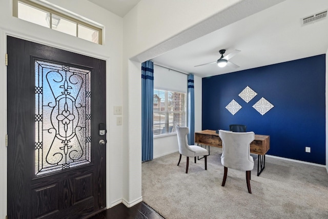 foyer entrance with visible vents, ceiling fan, baseboards, and dark colored carpet