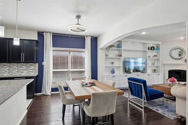 dining space featuring baseboards, a fireplace, and dark wood-style flooring