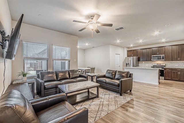 living area featuring visible vents, light wood-style flooring, and ceiling fan