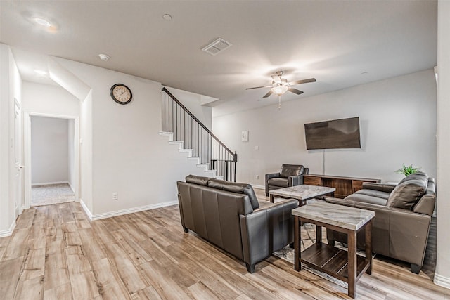 living area with visible vents, baseboards, stairway, light wood-style floors, and a ceiling fan