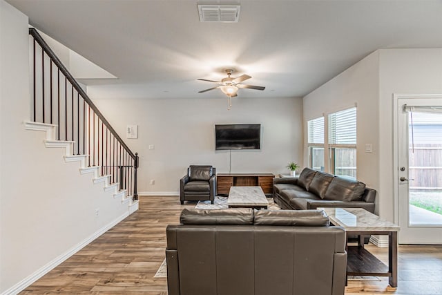 living room featuring visible vents, baseboards, stairs, wood finished floors, and a ceiling fan