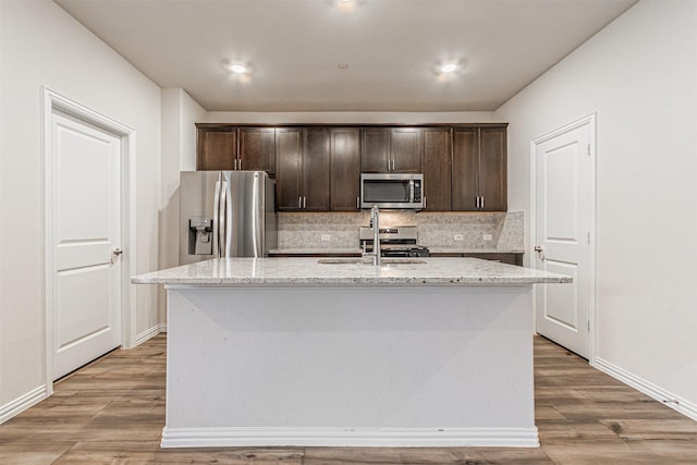 kitchen with decorative backsplash, dark brown cabinets, appliances with stainless steel finishes, and a sink