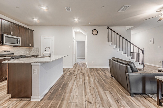 kitchen with ceiling fan, a sink, stainless steel appliances, dark brown cabinets, and light wood-type flooring